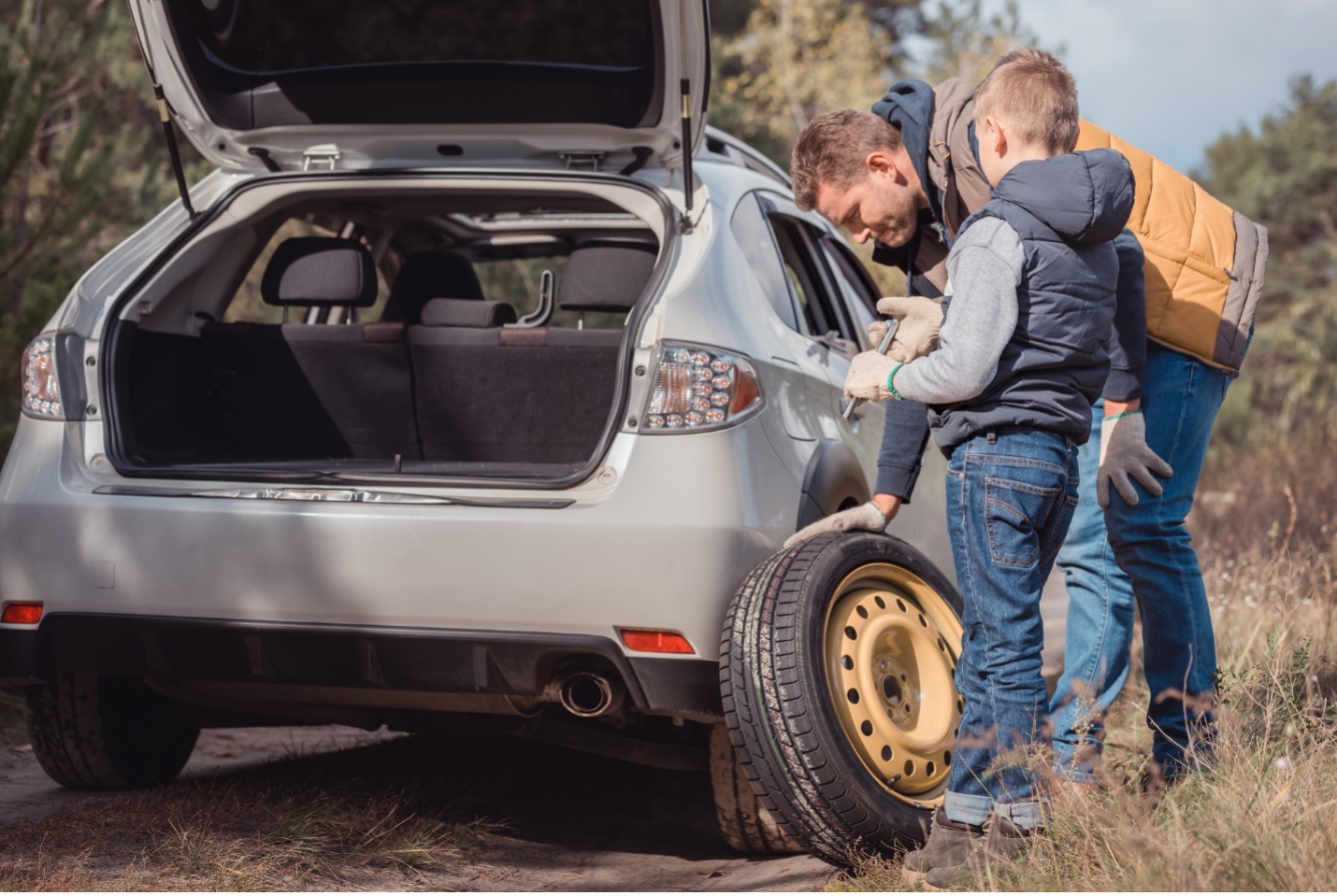 Father and son changing tire on car