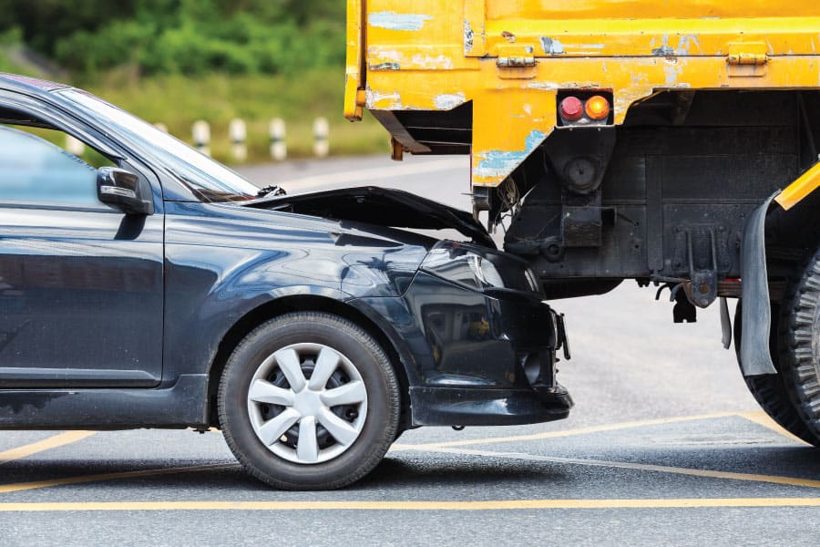 Vehicle crash involving a black car and a yellow truck on the highway.